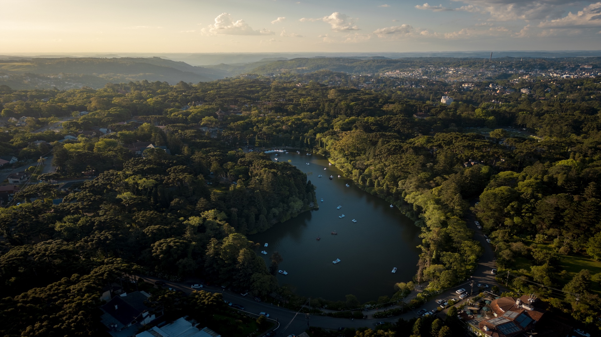Vista aérea do Lago Negro em Gramado, rodeado por mata verde e pedalinhos no lago