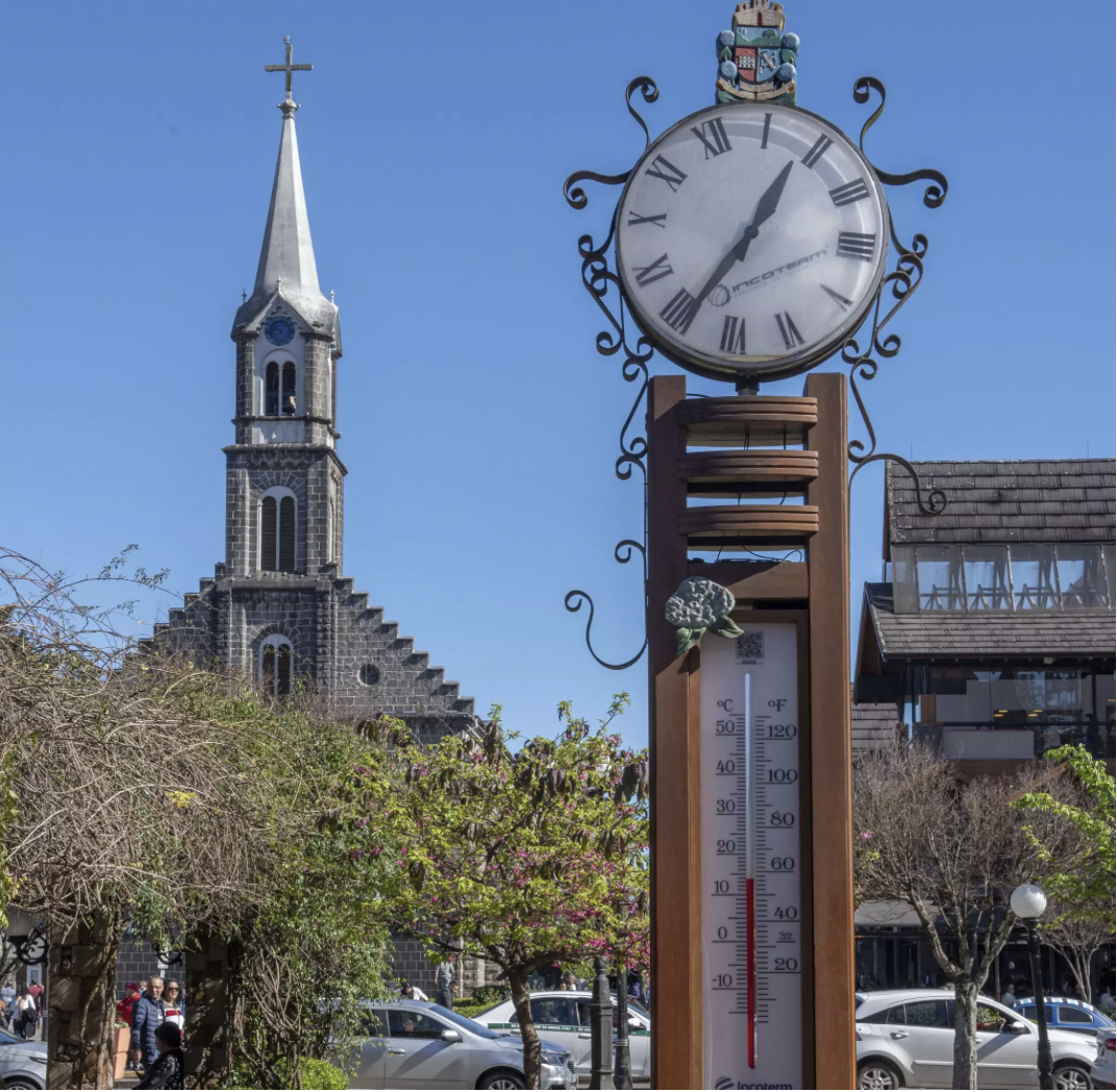 Relógio termômetro no centro de Gramado com a Igreja Matriz São Pedro ao fundo em um dia ensolarado